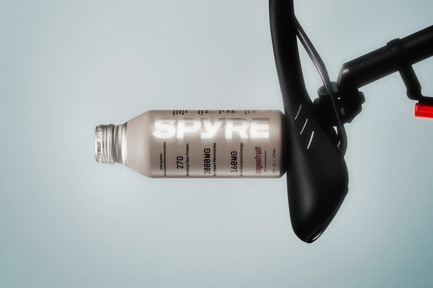 SPYRE sports drink packaging brand identity design — multi-bottle lineup with near-white ground and slate-blue accent