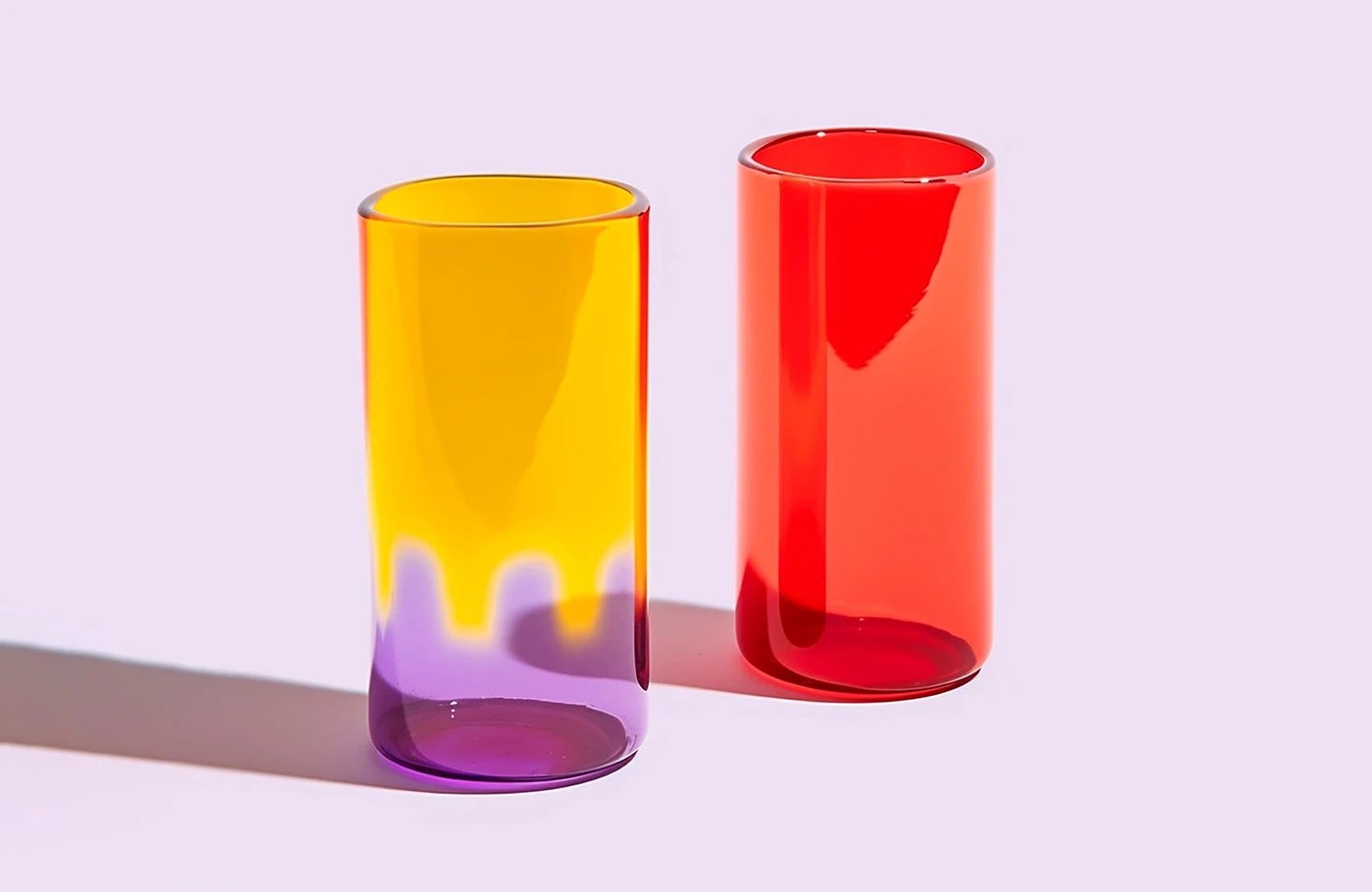 Image 5: Grandiose Collection glassware brand identity — ruby red and amber short tumblers on lavender background