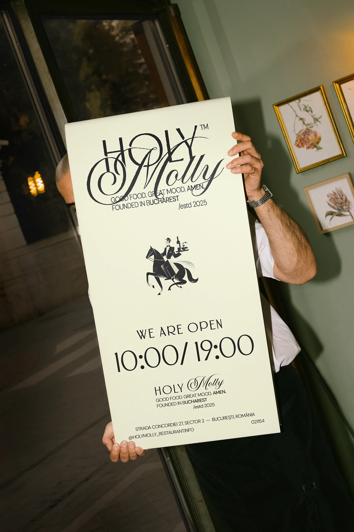 Image 2: Person holding tall Holy Molly poster card in black-and-white printed on cream stock — restaurant brand identity