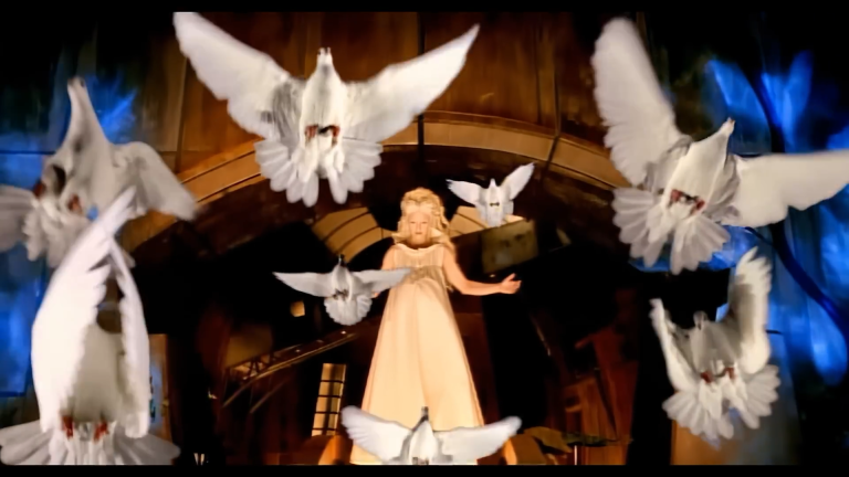 Image 1: Madonna in a pale gown surrounded by white doves in the Bedtime Story music video