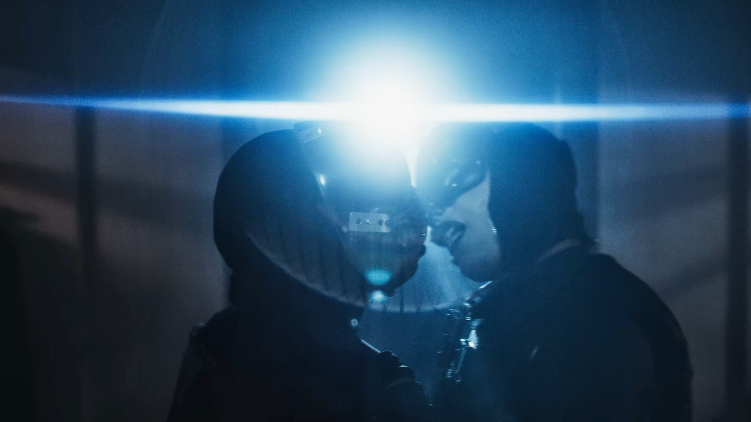 Image 4: Two masked figures touch foreheads in a beam of blue light in Confessions II