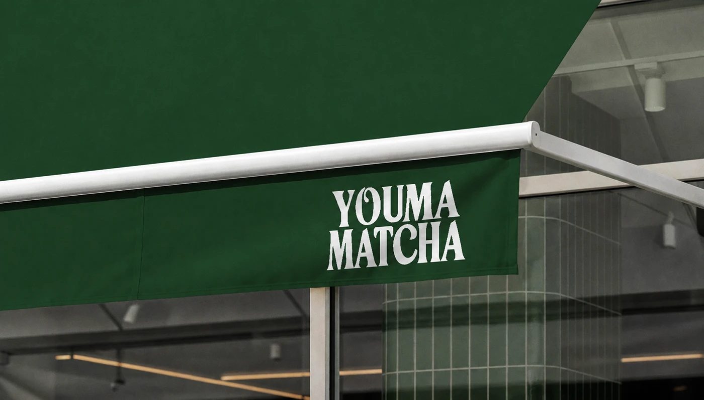 Image 3: Youma Matcha branding storefront green awning with serif logo